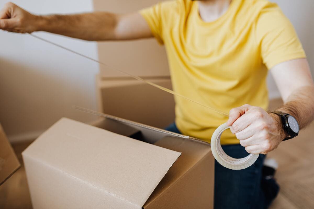 Homme scotchant des cartons